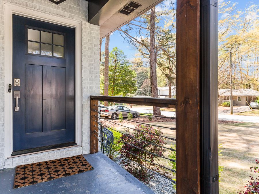 A navy front door and covered porch on a white brick home